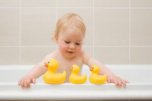 A baby boy looking at a row of rubber ducks